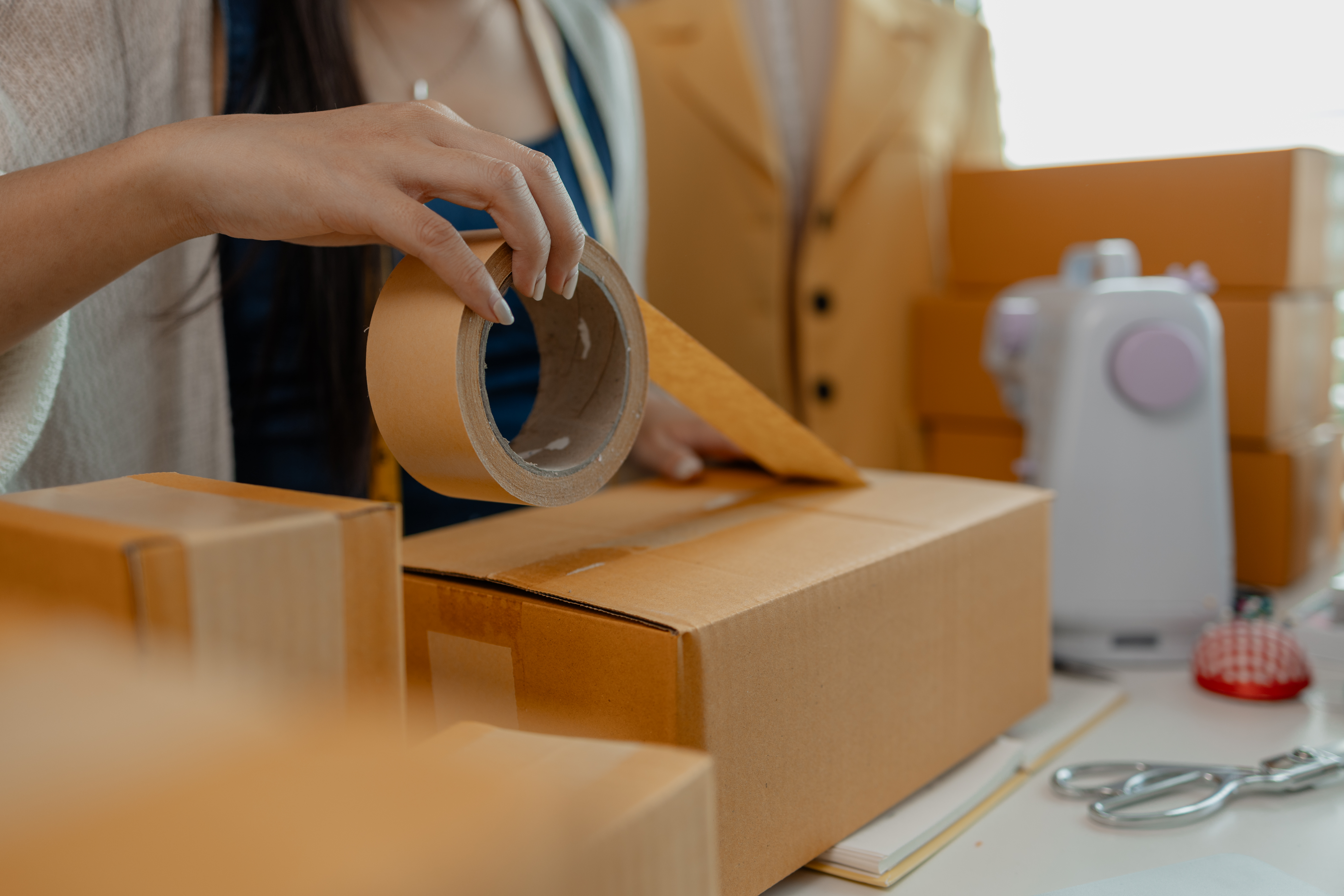 a woman taping up a brown shipping box