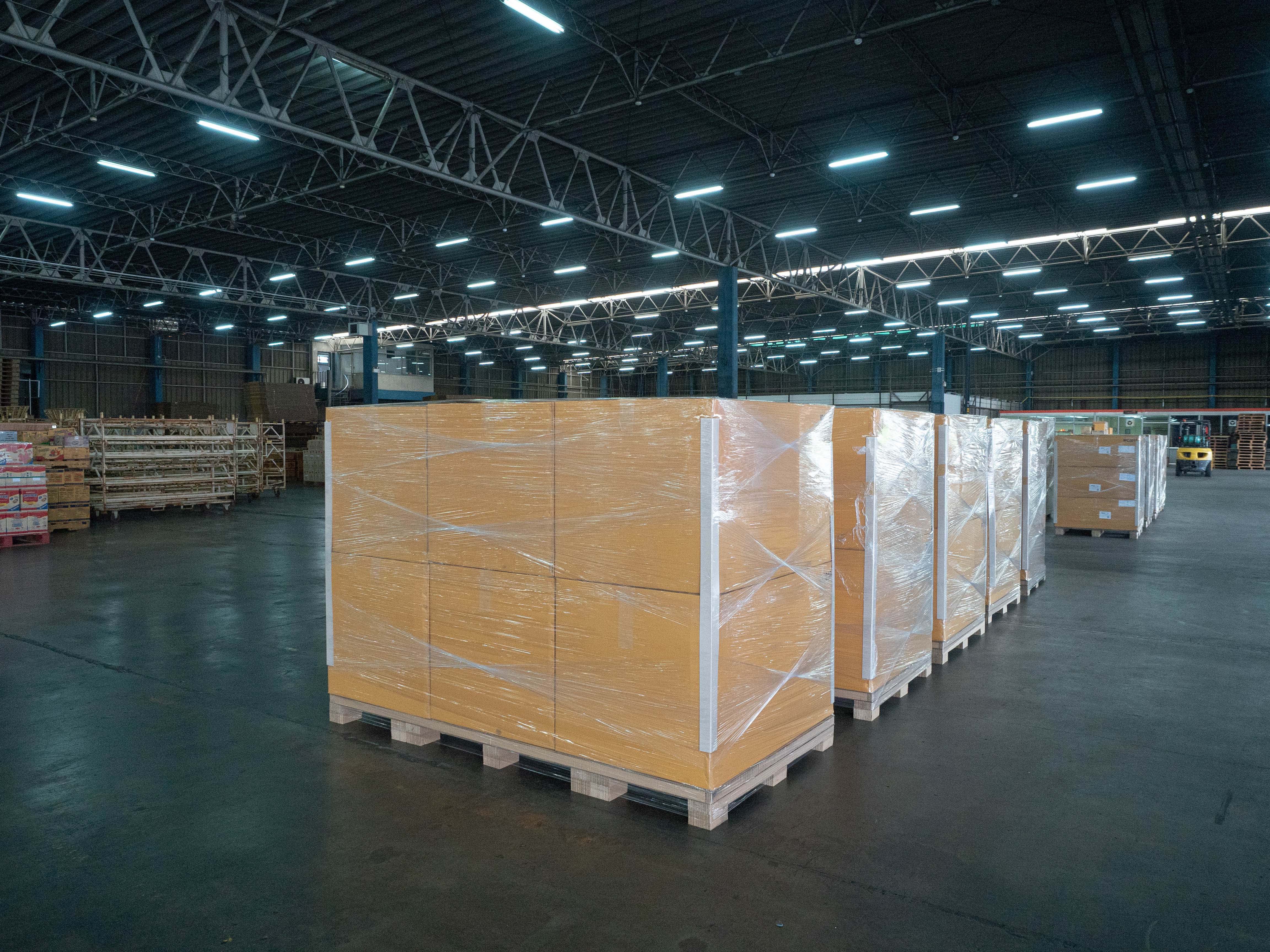 pallets of stacked cardboard boxes wrapped in stretch wrap in a large warehouse 