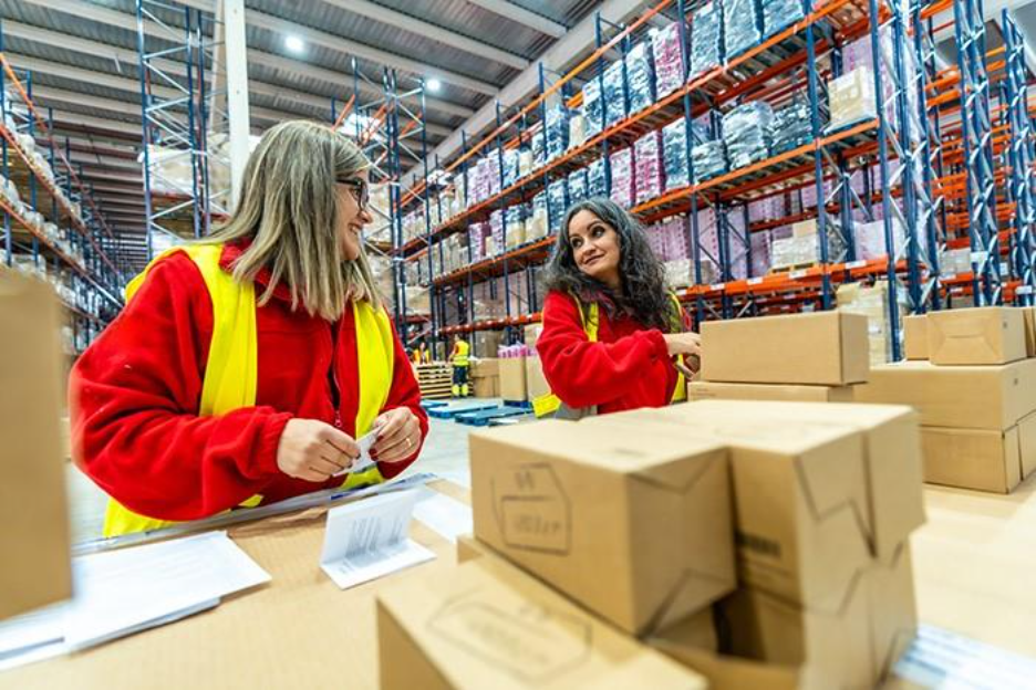 two women in a warehouse talking around boxes