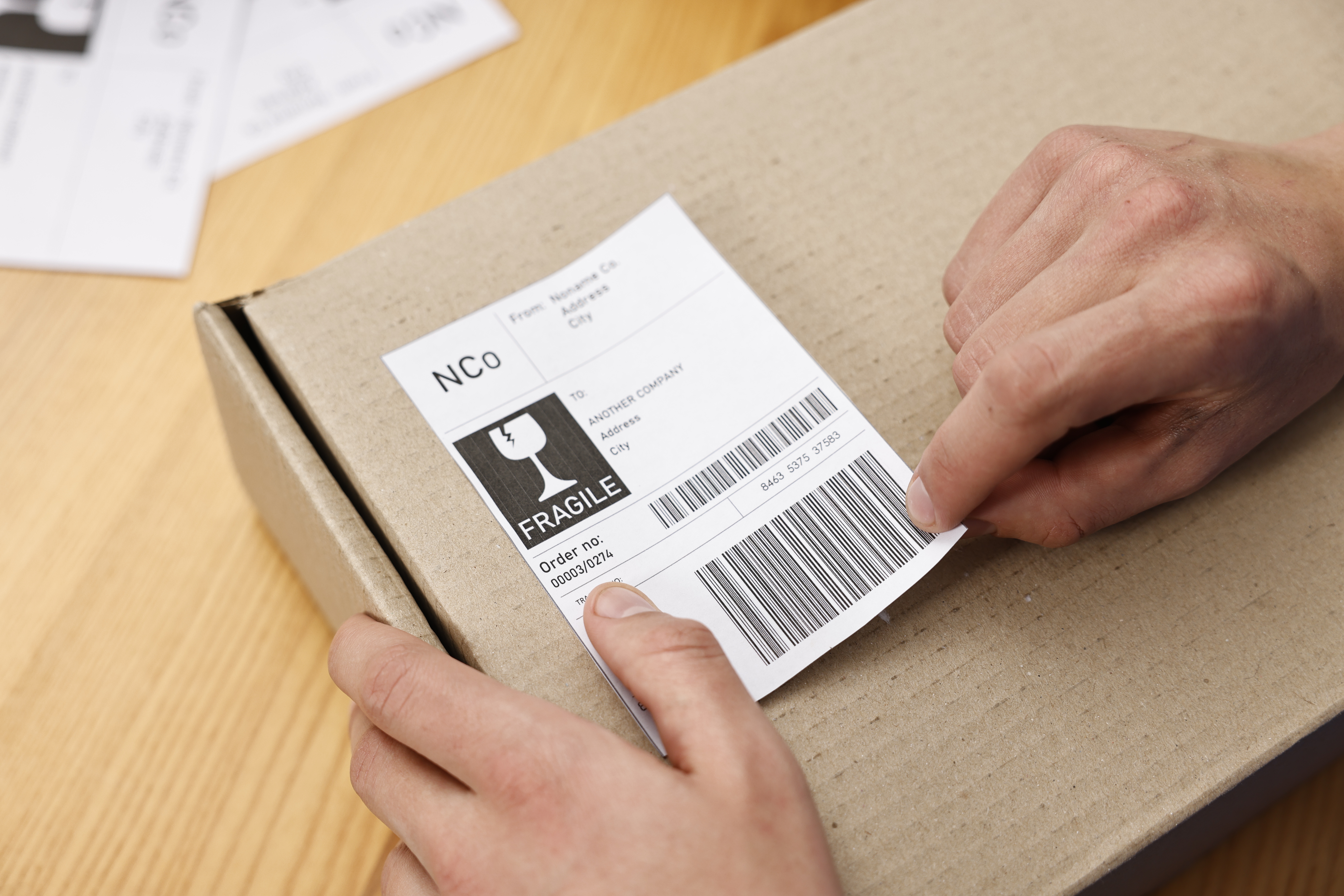 man sticking shipping label with barcode on package