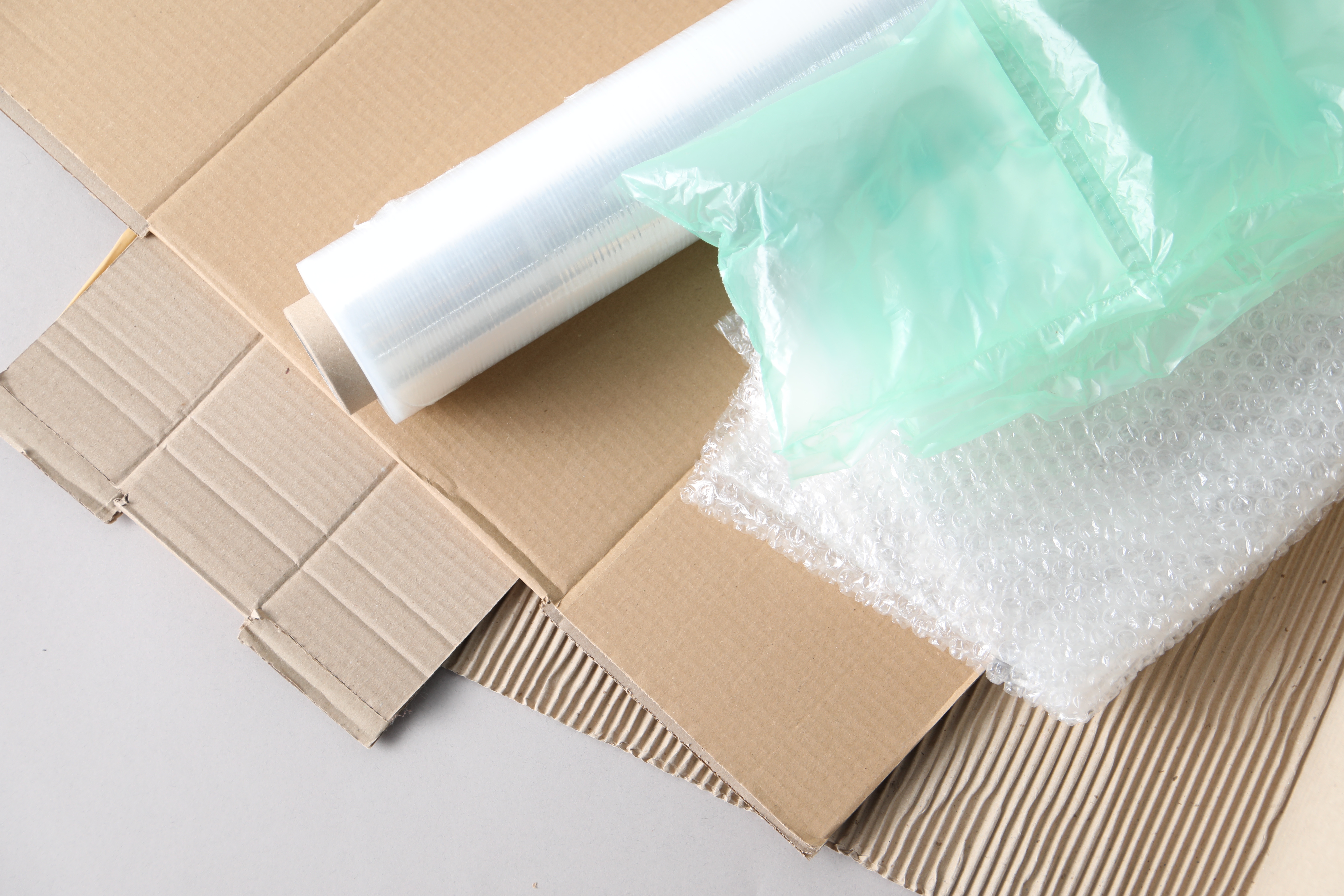 un-folded cardboard boxes on the ground with bubble wrap and a role of plastic wrapping on top