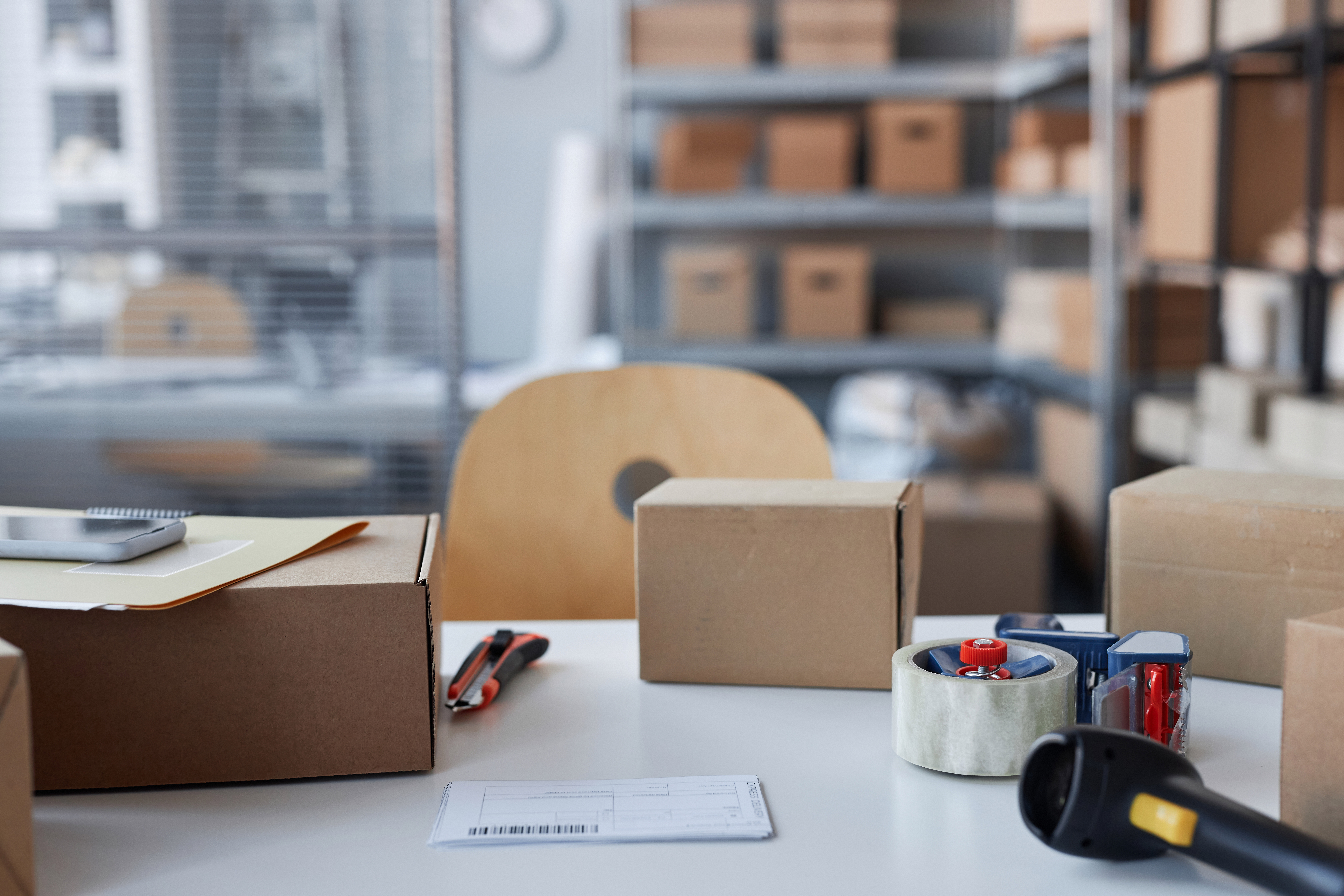 several brown packages on table with knife and cellotape