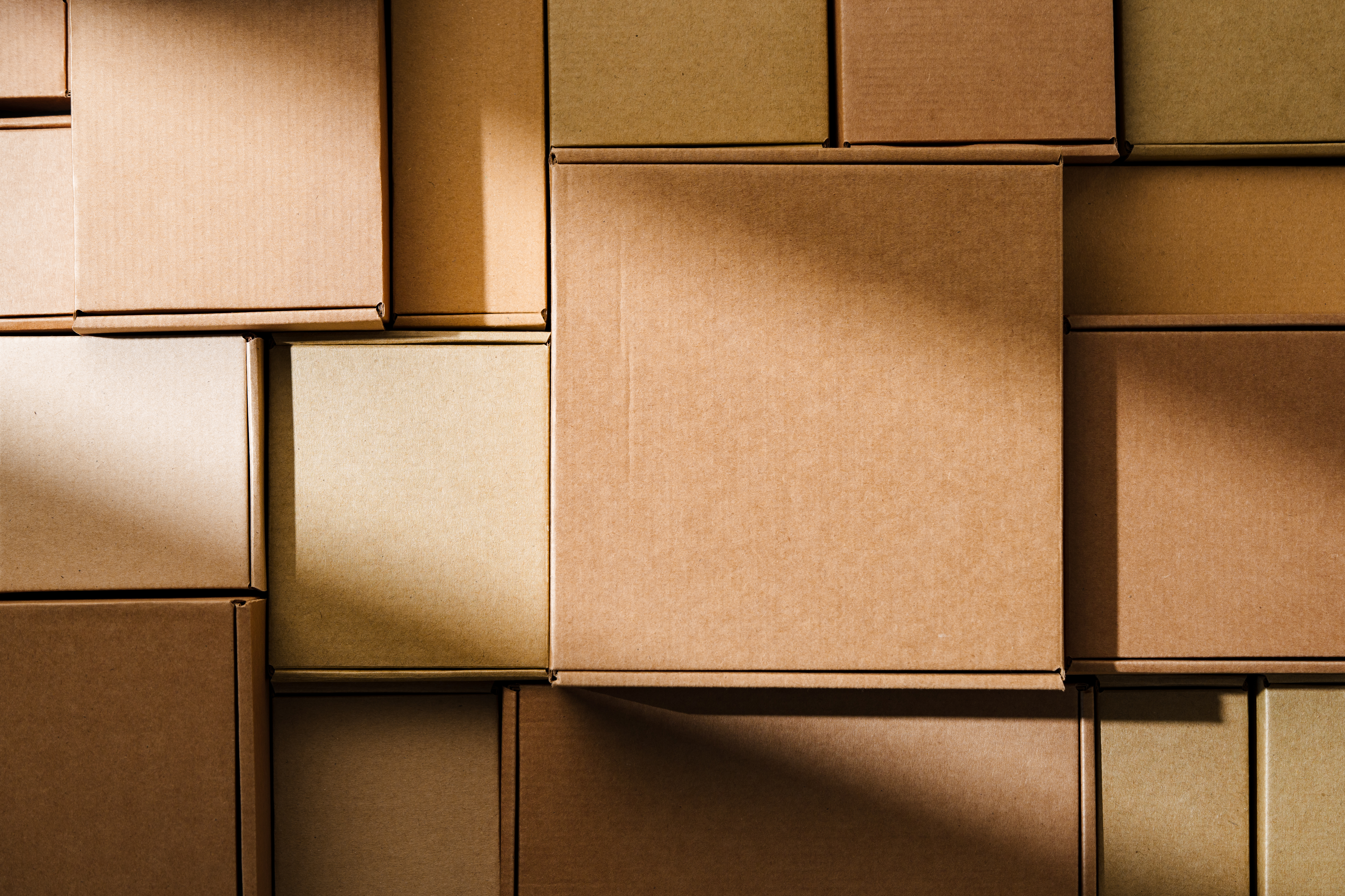 Close-up view of stacked brown cardboard boxes arranged in a geometric pattern, representing packaging, shipping, storage, or e-commerce fulfillment.