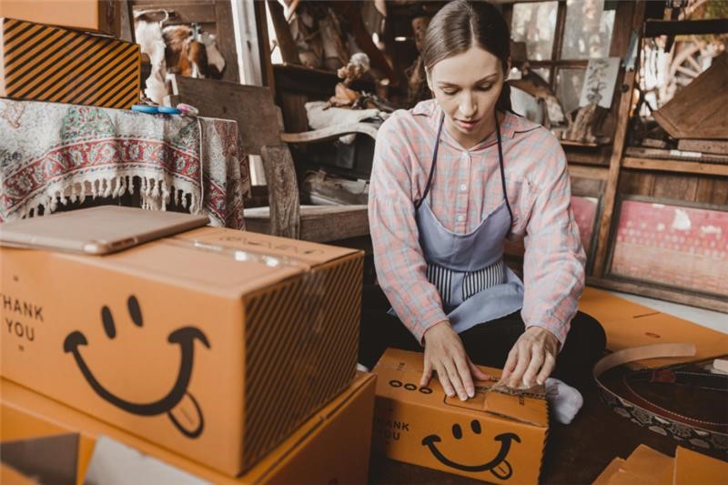 woman packing up custom shipping boxes with smiley faces on them