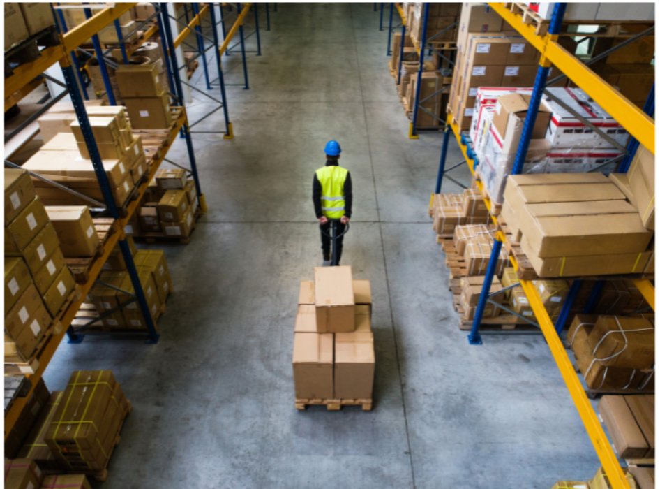 a man in a warehouse, pulling a pallet of boxes